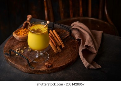 Turmeric golden milk latte with cinnamon sticks and honey. Healthy ayurvedic drink. Trendy Asian natural detox beverage with spices for vegans. Copy space.