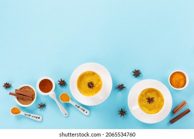 Turmeric golden milk latte with spices, cinnamon and honey on blue background. Detox, immune boosting, anti inflammatory healthy winter traditional indian drink. Top view, copy space.