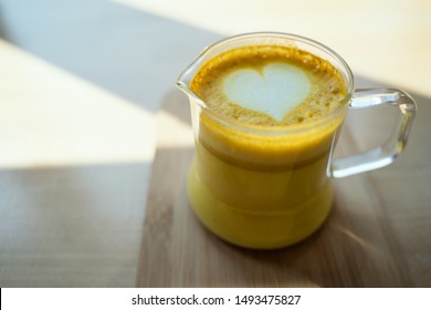Turmeric latte mix, golden milk in a cafe with latte art of a heart. Trendy coffee alternative concept