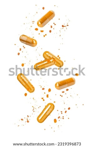 Turmeric powder capsule falling in the air isolated on white background.