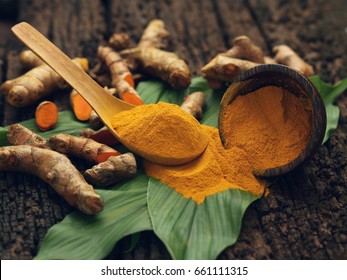 Turmeric powder and fresh turmeric on wooden background.