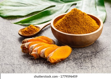 Turmeric powder and fresh slices of turmeric root on grey concrete background. Spice, natural coloring, alternative medicine.