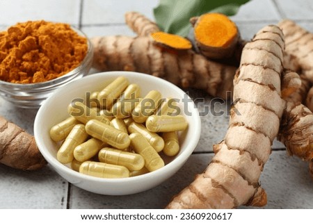 Turmeric roots, pills and powder on light tiled table, closeup