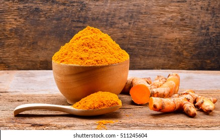 Turmeric roots with turmeric powder on wooden background