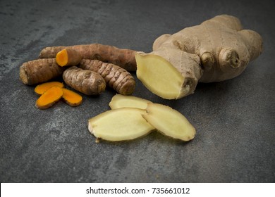 turmeric slices and ginger root sliced on gray background
