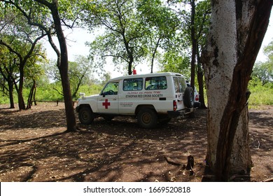 Turmi, Ethiopia, Africa, February 21, 2020. Red Cross Ambulance Parked In The Shade Of The Trees Of A Mursi Tribe Settlement