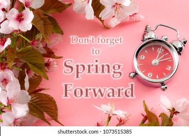 Turn Clocks One Hour Ahead, Start Of Daylight Savings Time Change And Reminder To Spring Forward Concept With Clock On Pink Background With Springtime Flowers And Text - Don't Forget To Spring Forward