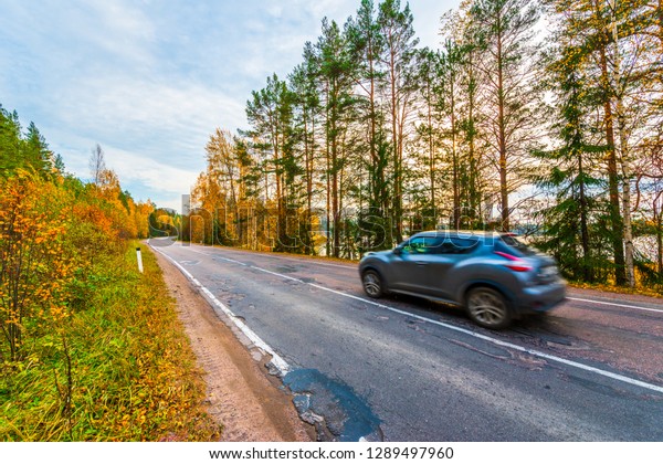 Turn the\
country broken road. The car goes on the road. Mixed forest. Sunset\
over the forest lake. Autumn weather. Beautiful nature. Russia,\
Europe. View from the side of the\
road.