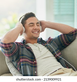 Turn Down The Week, Turn Up The Music. Shot Of A Young Man Relaxing On The Sofa And Listening To Music With Headphones At Home.