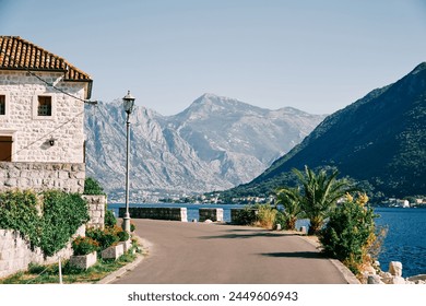 Turn of the embankment road near an ancient stone building with flowering flower beds - Powered by Shutterstock