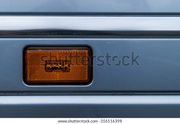 A turn signal lamp of a\
grey truck
