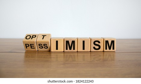 Turned a cube and changed the expression 'pessimism' to 'optimism'. Beautiful wooden table, white background. Business concept. Copy space.