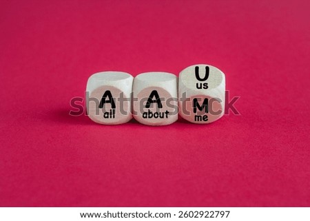 Turned a cube and changes the expression AAM (all about me) to AAU (all about us). Beautiful red background, copy space.