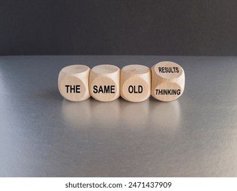 Turned a cube and changes expression 'the same old thinking' to 'the same old results'. Beautiful grey table, black background. Business concept. Copy space.