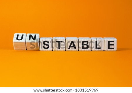 Turned cubes and changed the word 'unstable' to 'stable' or vice versa. Beautiful orange background. Business concept. Copy space.