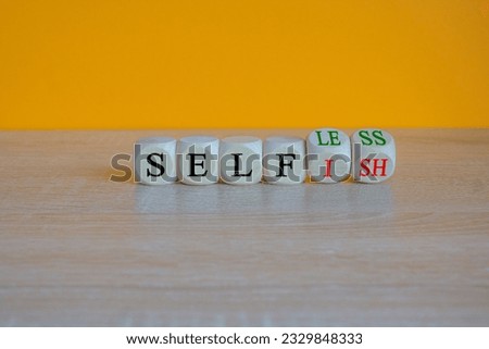 Turned cubes and changes the word 'selfish' to 'selfless'. Beautiful orange background, copy space. Business, psuchological and selfish or selfless concept.