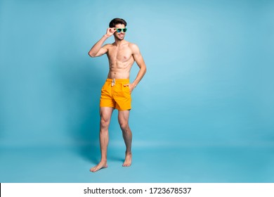 Turned full length body size photo of cheerful positive handsome man walking looking at people at beach isolated pastel color blue background