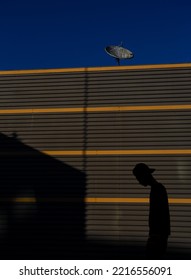 A Turned Off Antenna Against A Dark Blue Sky And A Sad Boy Silhouette Walking To A No Reception Home. 