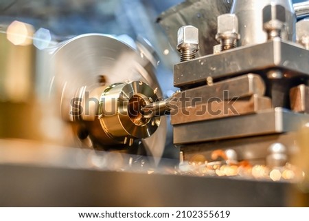 A turner bores a hole in a bronze part on a lathe with a power tool.