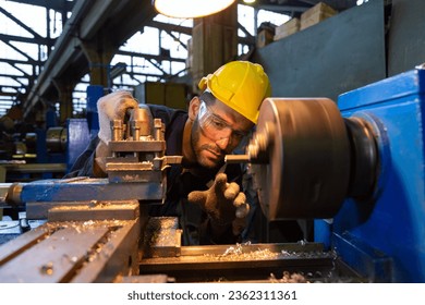 Turner, male-female workpiece He is turning work in a blue jumpsuit and wearing a safety hard hat. - Powered by Shutterstock