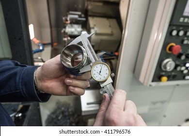 Turner miller verifies the accuracy of manufacturing steel parts with a special caliper Additional scale - the size of the measurement device. In the background to blur milling machine.