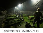 Turning in after a hard day of training. Soldiers getting ready to bunk down inside of their large tent.