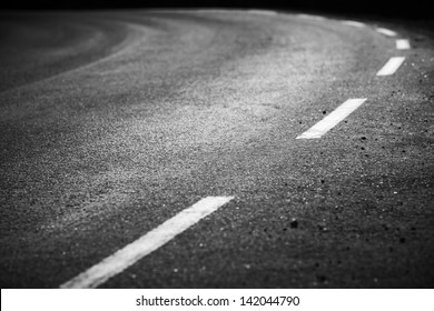 Turning asphalt road with marking lines and tire tracks. Close up photo with selective focus - Powered by Shutterstock