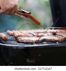 Turning Hotdogs On Grill With Tongs