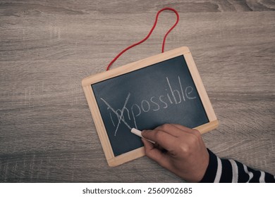 Turning the impossible into the possible. Impossible written with white chalk on a blackboard in woman's hands. Motivation for success, away with doubts - Powered by Shutterstock