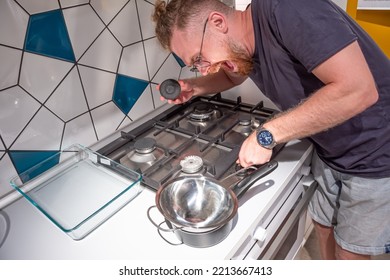 Turning Off The Gas At Home Kitchen, Shortages And Saving Stocks For The Wintering Of Europeans. The Concept Of A Surprised Man In Disbelief Is Surprised By The Disconnected Gas In The Apartment