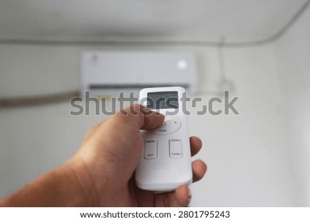 Turning On Air Conditioner Using Remote Control with Comfortable Indoor Cooling Scene