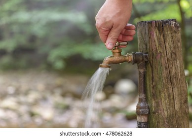 Turning on or shutting off an outdoor water faucet in the woods.