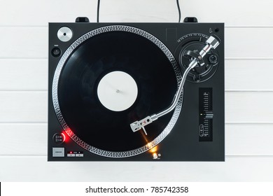 Turntable Vinyl Record Player On The Background White Wooden Boards. Sound Technology For DJ To Mix & Play Music. Needle On A Vinyl Record. Black Vinyl Record