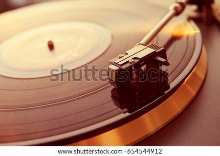 Turntable vinyl record player on the background of a sunset over the lights city. Sound technology for DJ to mix & play music. Black vinyl record. Vintage vinyl record player. Needle on a vinyl record