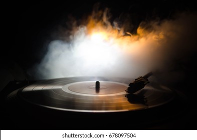 Turntable vinyl record player. Retro audio equipment for disc jockey. Sound technology for DJ to mix & play music. Vinyl record being played against burning fire background with smoke