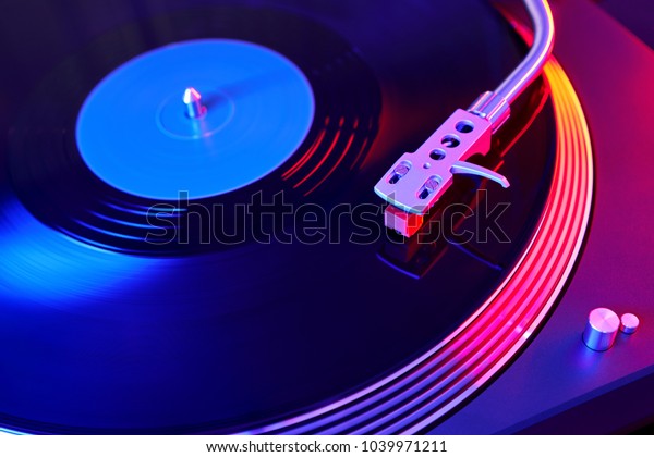Turntable vinyl record player. Sound technology for DJ\
to mix & play music. Vintage vinyl record player on a\
background decorations for a party, bright disco lights. Needle on\
a vinyl record   