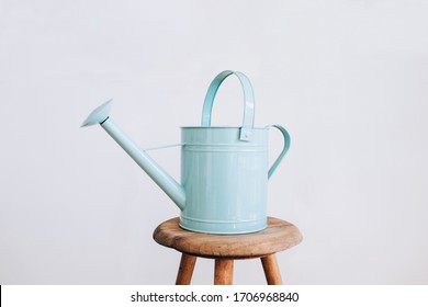 A turqoise watering can on a wooden stool