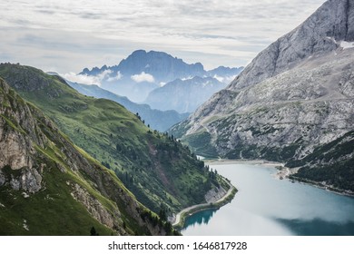 Turquoise alpine lake in between mountain cliffs and forest trees 