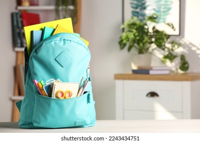 Turquoise backpack with different school stationery on white table indoors, space for text - Powered by Shutterstock