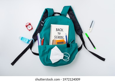 Turquoise Backpack With School Supplies And Kid Face Mask On White Background, Top View