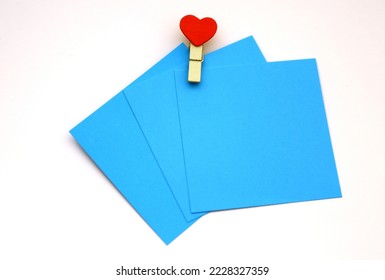 Turquoise, blue colored note papers shot on White while heartshape clothespin hold them.