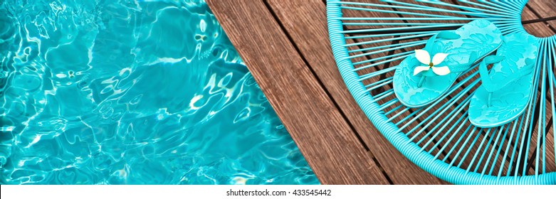 Turquoise blue garden chair and flip flopson on the edge of a swimming pool, panoramic view