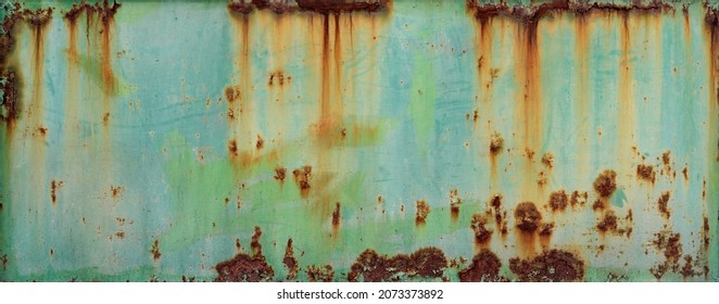 turquoise blue and green wall or surface of a fence of metal, with orange grooves from rust and irregular chipping - weathered texture for the background of a steampunk wallpaper