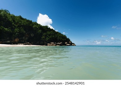 Turquoise Caribbean waters meeting a rocky coastline, surrounded by lush green hills under a bright blue sky. A peaceful tropical escape showcasing nature’s raw beauty and tranquility. - Powered by Shutterstock