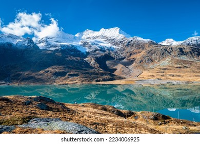 Turquoise colored lake "Lago Bianco" with snow capped mountains of the Bernina Range in the background. - Powered by Shutterstock