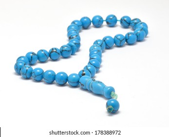 Turquoise Islamic prayer beads isolated on white under studio lighting