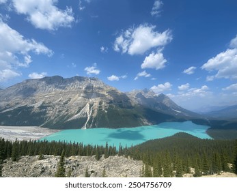 Turquoise lake, pine forests, and rugged mountains under a bright blue sky. - Powered by Shutterstock