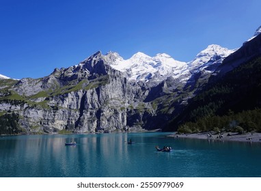 Turquoise Lake with Snow-Capped Mountains, Kayaking Tourists, Forest, and Sunny Blue Sky                                - Powered by Shutterstock