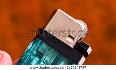 A turquoise lighter with metallic elements. The focus highlights the textured ignition wheel and the overall sleek design