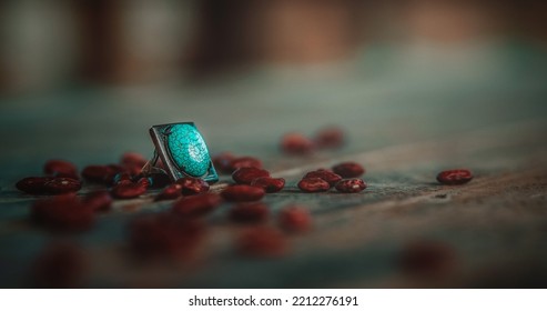 Turquoise Ring On A Table Surrounded By Bean Seeds